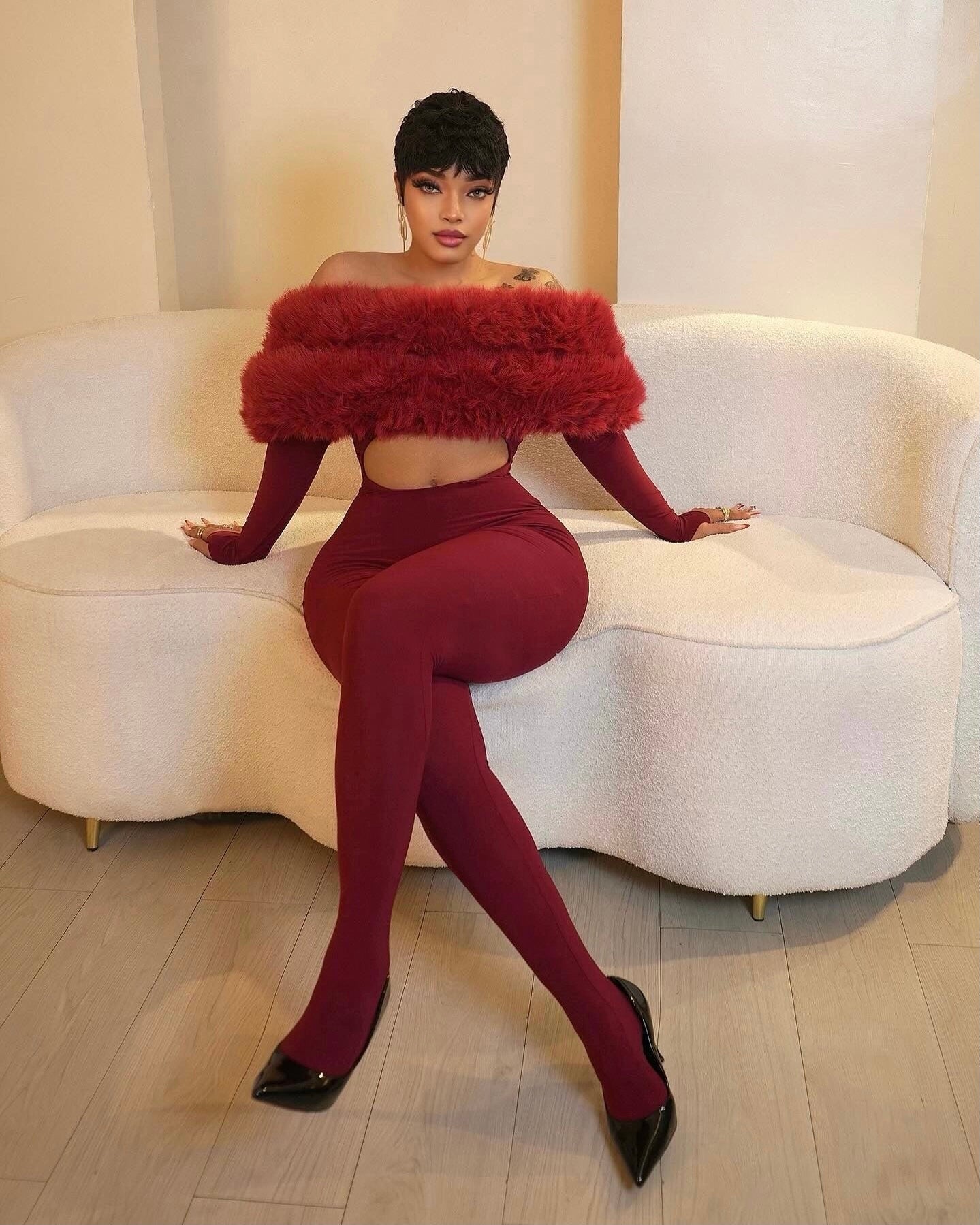 A woman wearing a burgundy fitted jumpsuit styled for a night out