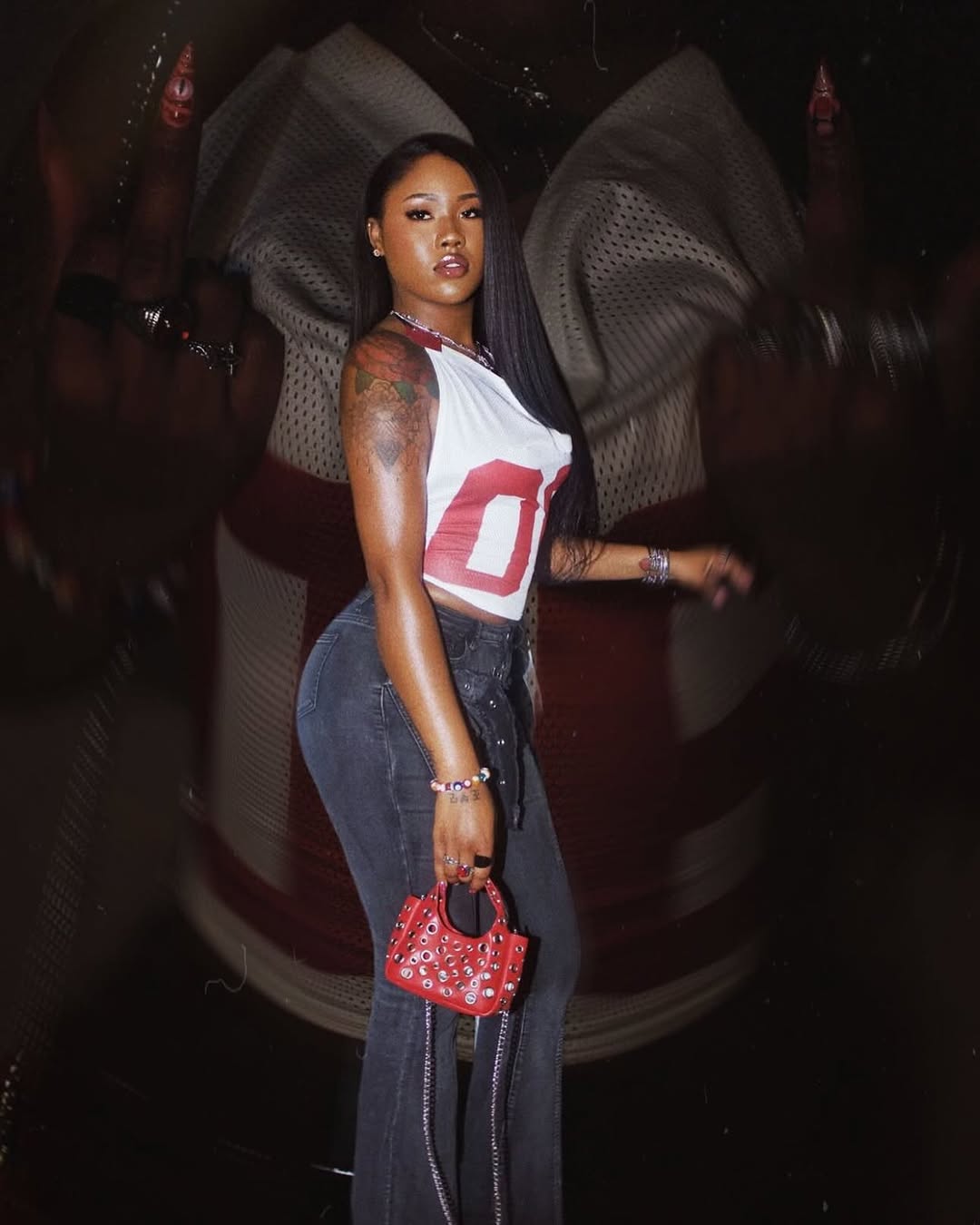 A stylish woman wearing a sporty mesh corset top with a red and white jersey-inspired design.