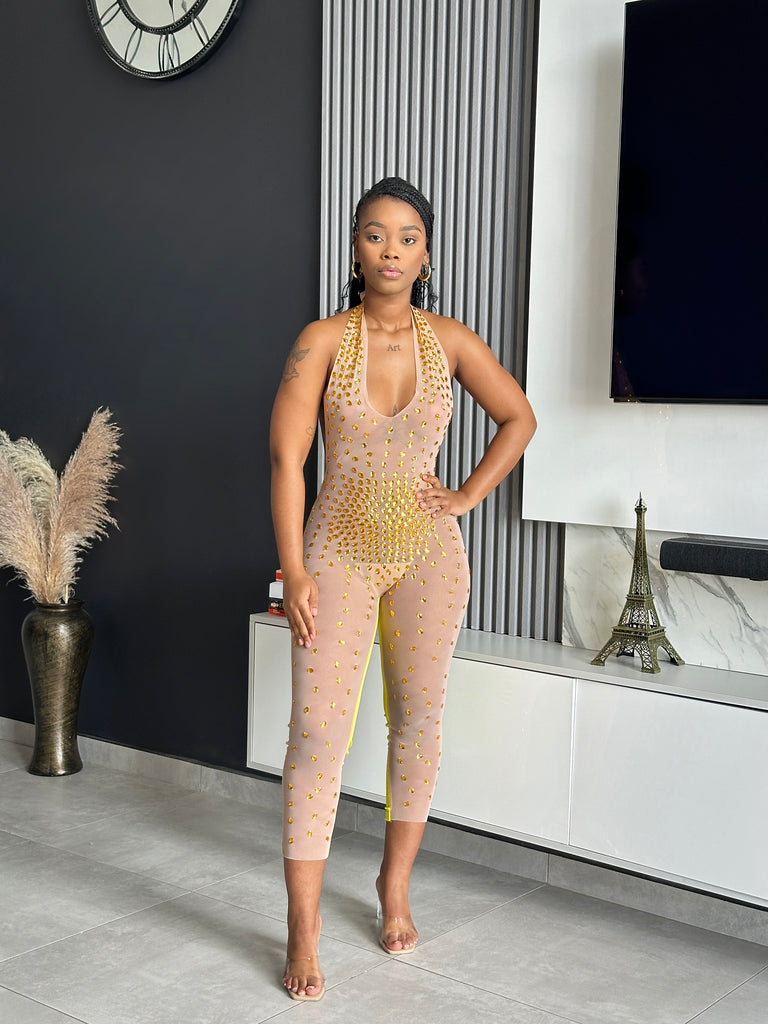 A woman wearing the Me Wow Jumpsuit, a sheer mesh halter-neck jumpsuit with golden rhinestone details, ideal for special occasions