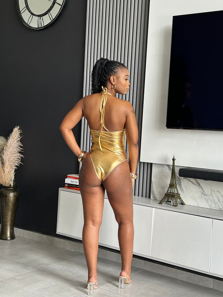 Model wearing the Majesty Gold Cutout Bodysuit with metallic finish, bold cutouts, and chain details for a glamorous look.