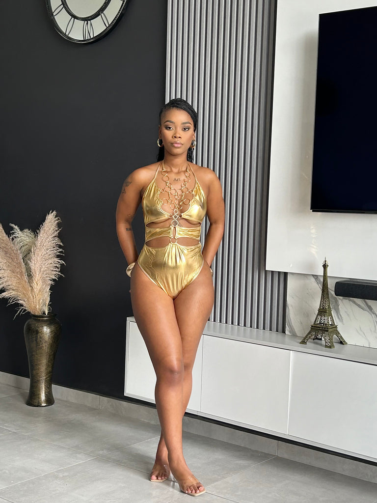 Model wearing the Majesty Gold Cutout Bodysuit with metallic finish, bold cutouts, and chain details for a glamorous look.