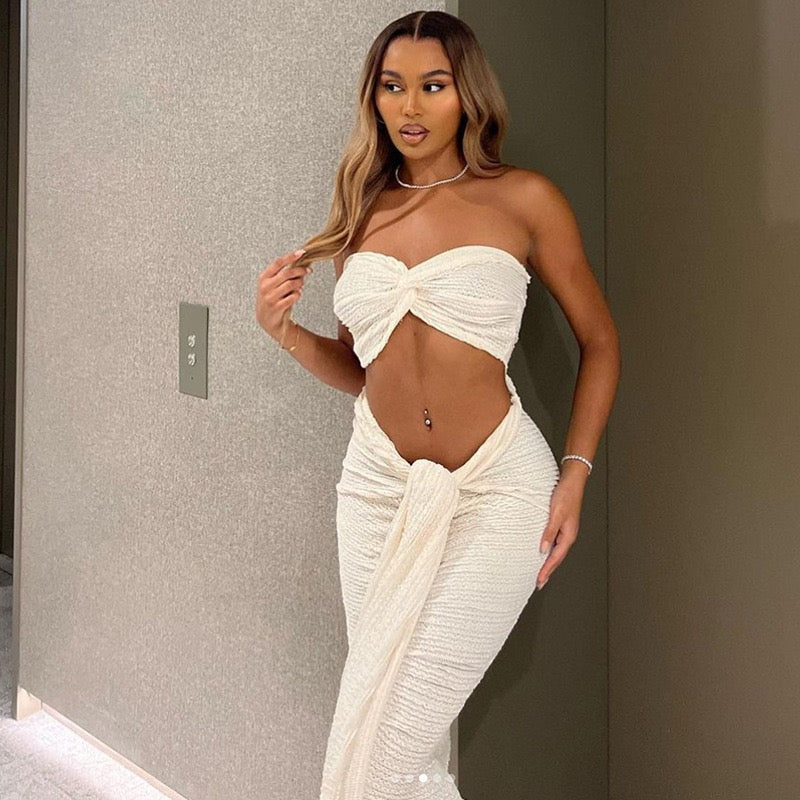 Woman wearing the Arianna Two-Piece Set, featuring a white bandeau top and high-waisted maxi skirt with draped detail.