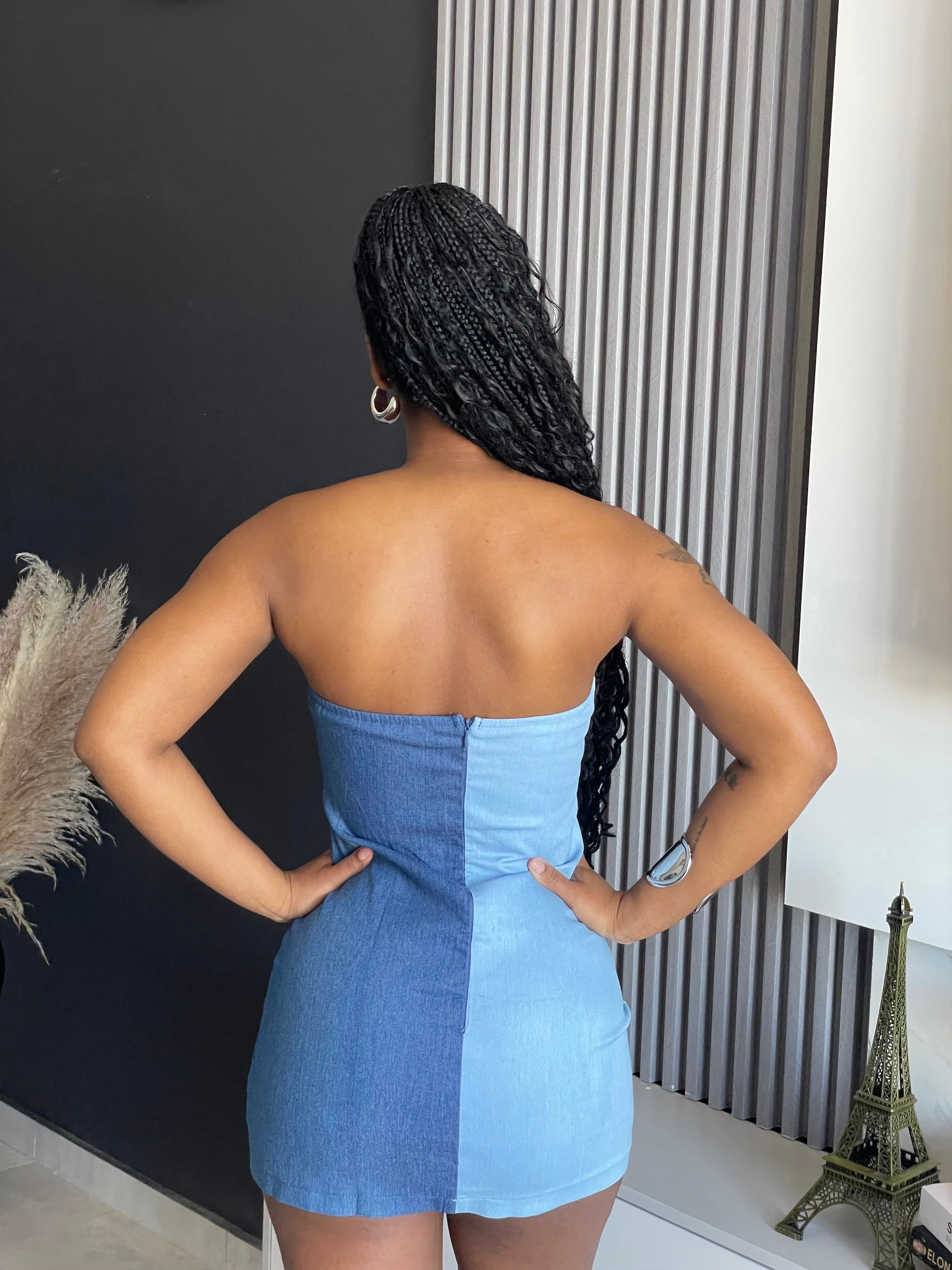 A woman wearing the Bandia Denim Mini Dress, showcasing its strapless design and playful ruffles, perfect for both casual and sophisticated settings