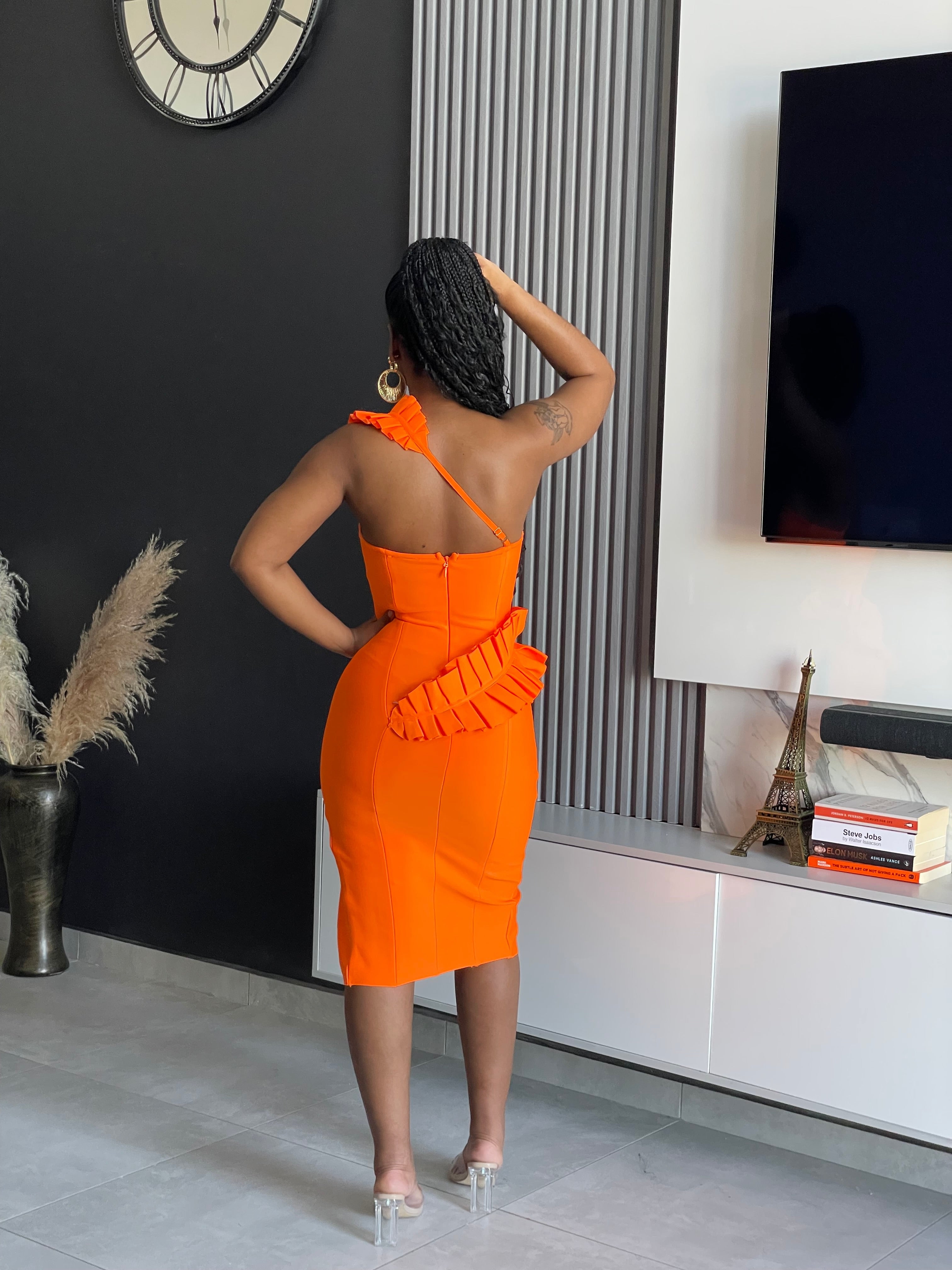 A woman in an XS size Breath Taking Bandage Midi Dress in vibrant orange with ruffle detailing, ideal for special occasions