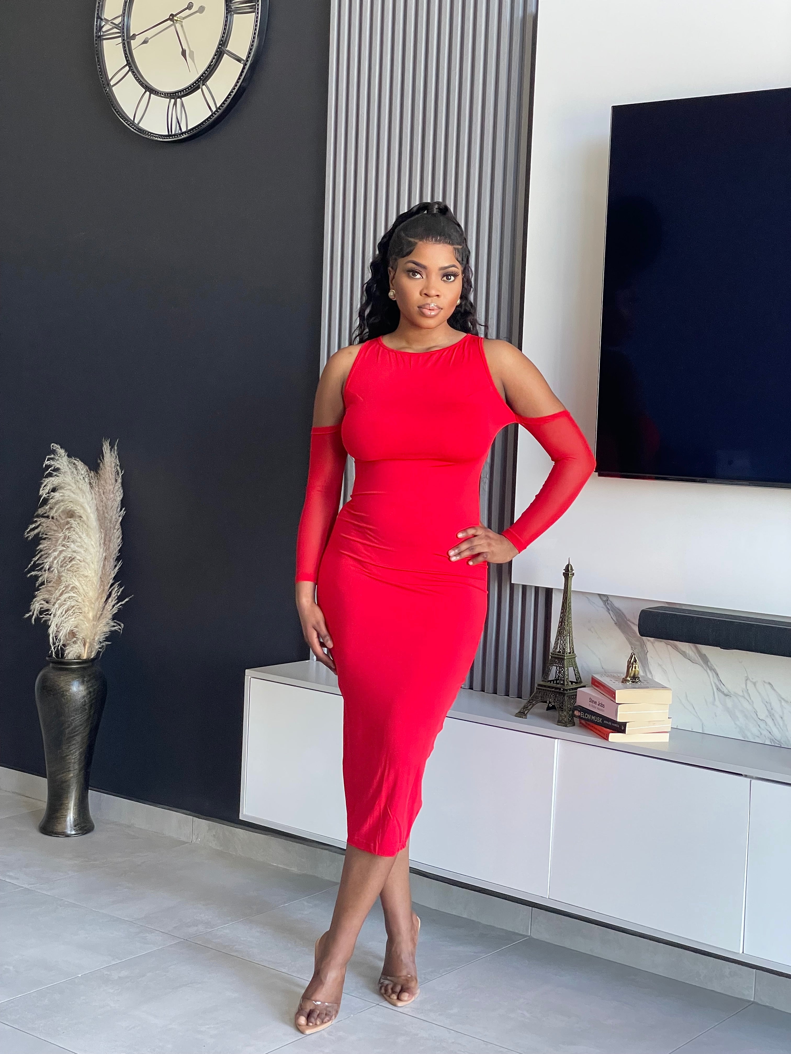 A woman in a vibrant red Paisy Midi Dress with unique sleeve cut-outs, exuding elegance and confidence