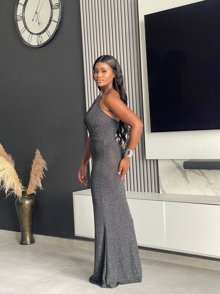 Model wearing Winners Circle Maxi Dress in charcoal grey, featuring a glittery finish and elegant cutout, ideal for formal occasions.