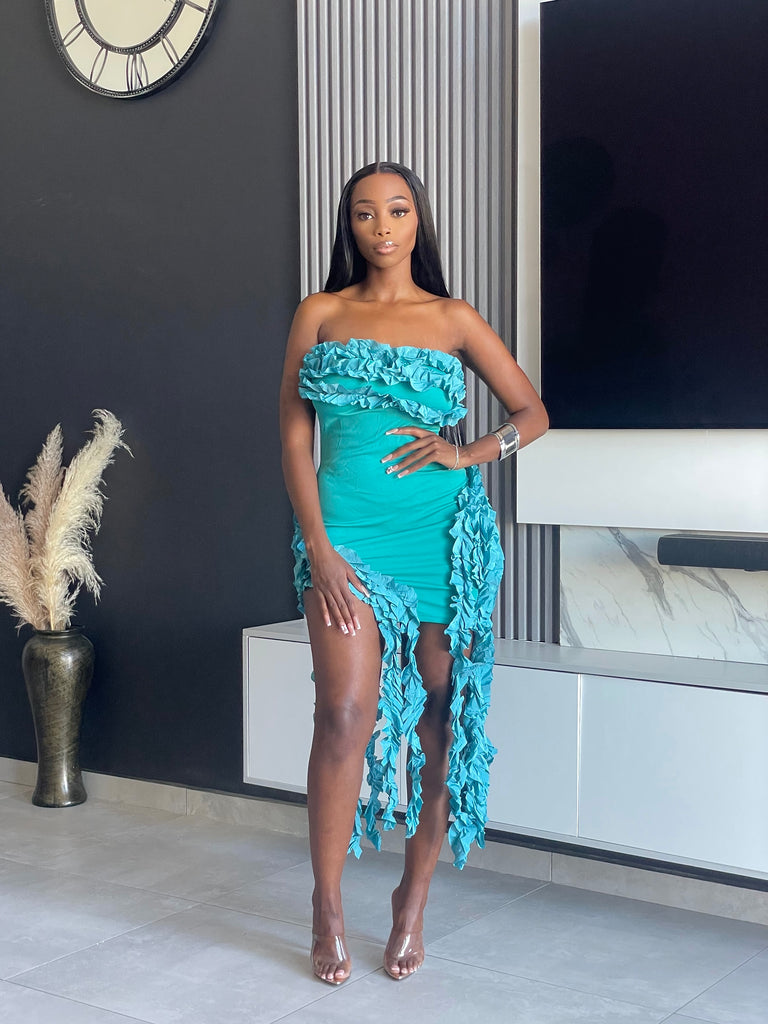 Model wearing the Doll Tassel Dress in teal with strapless design, ruffle detailing, and tassel accents.