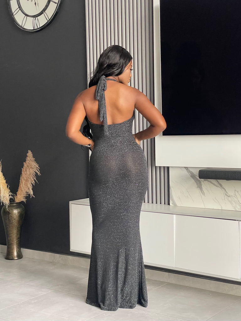 Model wearing Winners Circle Maxi Dress in charcoal grey, featuring a glittery finish and elegant cutout, ideal for formal occasions.