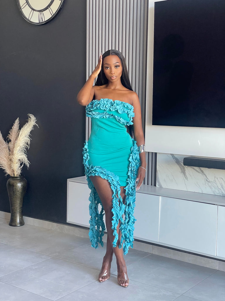 Model wearing the Doll Tassel Dress in teal with strapless design, ruffle detailing, and tassel accents.