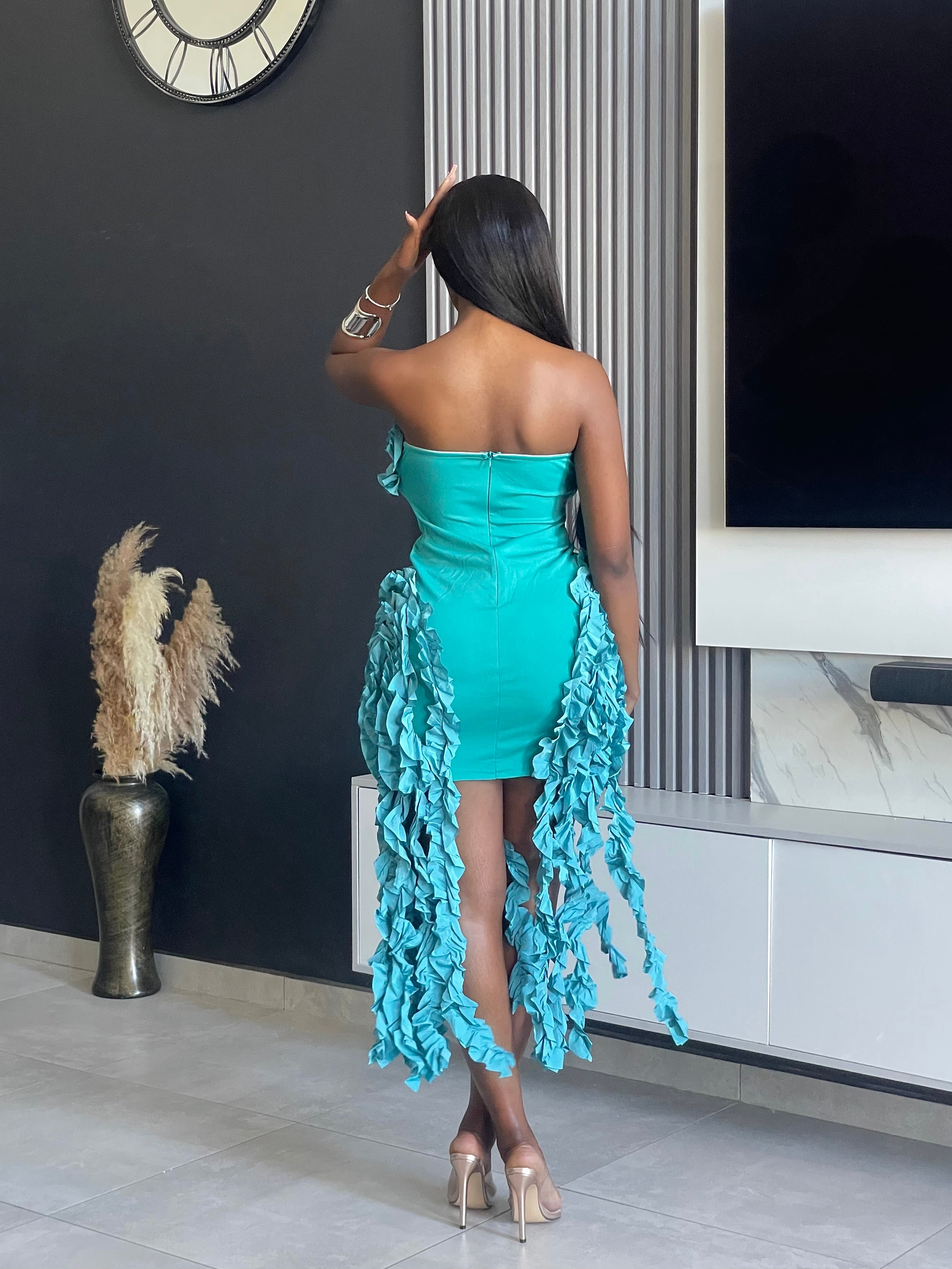 Model wearing the Doll Tassel Dress in teal with strapless design, ruffle detailing, and tassel accents.