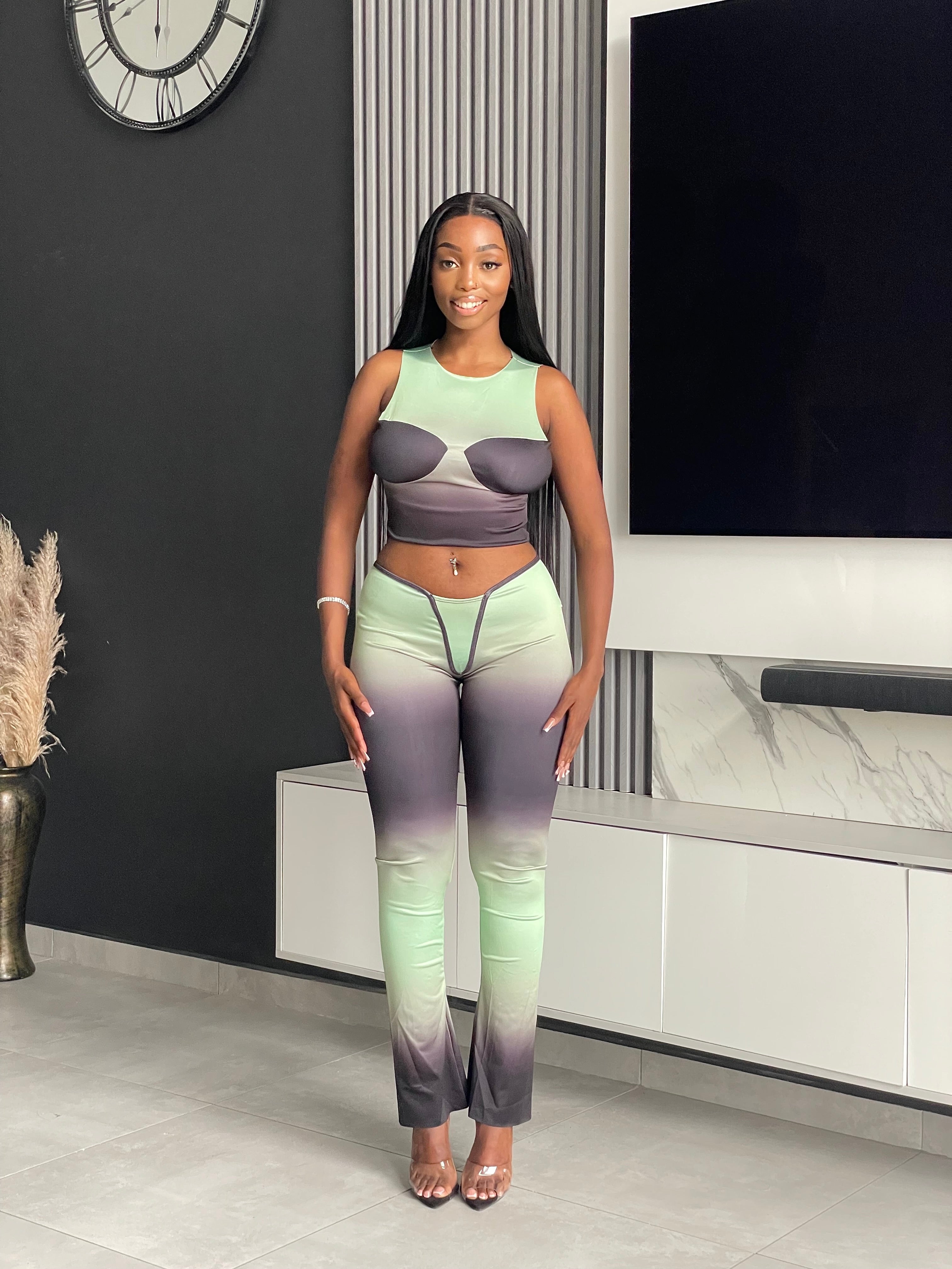 Model wearing the Pasty Pant Set, a chic ombre two-piece outfit with a fitted crop top and flared pants in green and black.