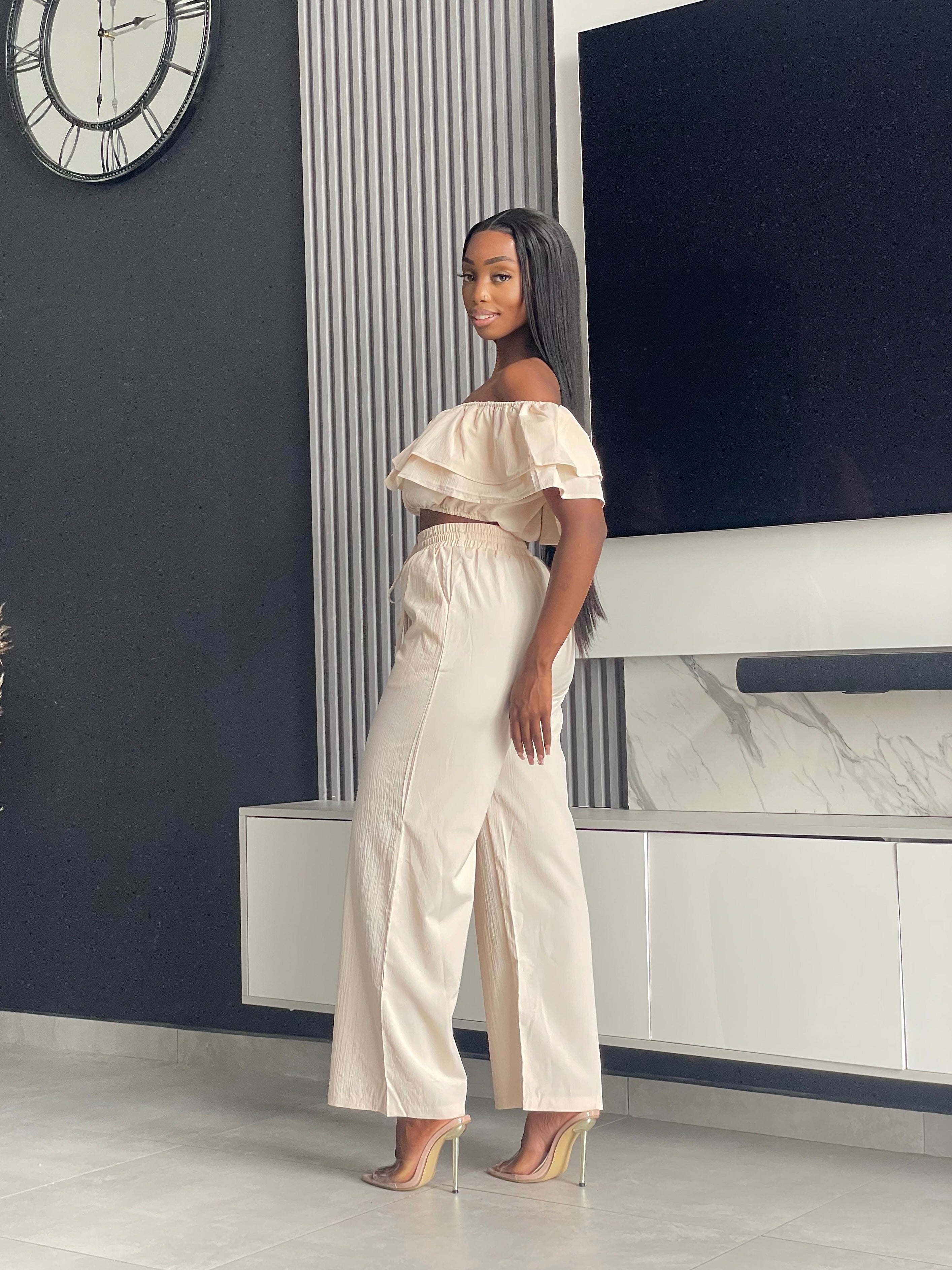 Model wearing the Varouna Pant Set in beige, featuring an off-shoulder ruffled crop top and wide-leg pants, perfect for casual outings.