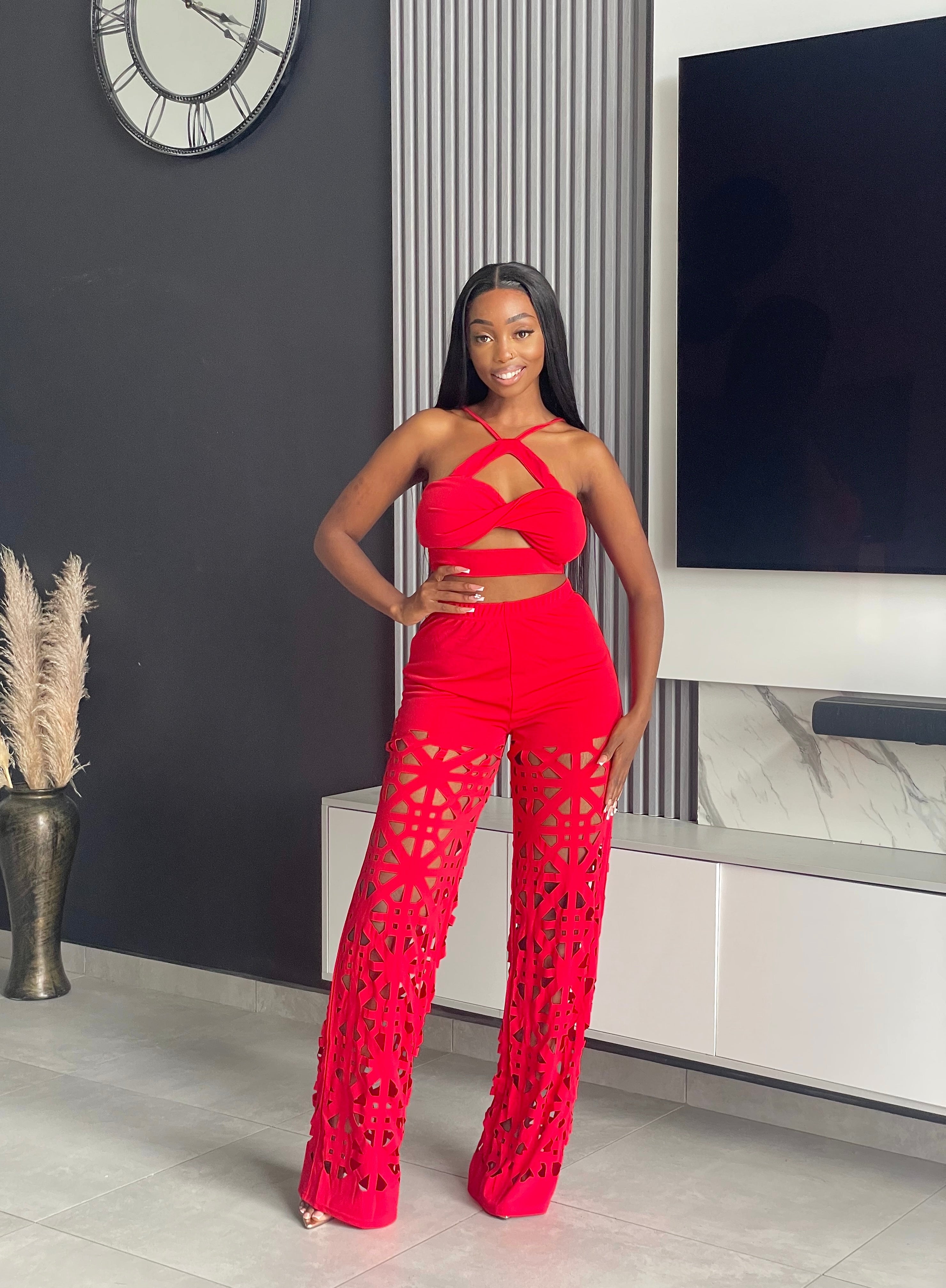 Model wearing the Remedy Pant Set in red, featuring a crisscross halter crop top and wide-leg pants with intricate cutout designs.