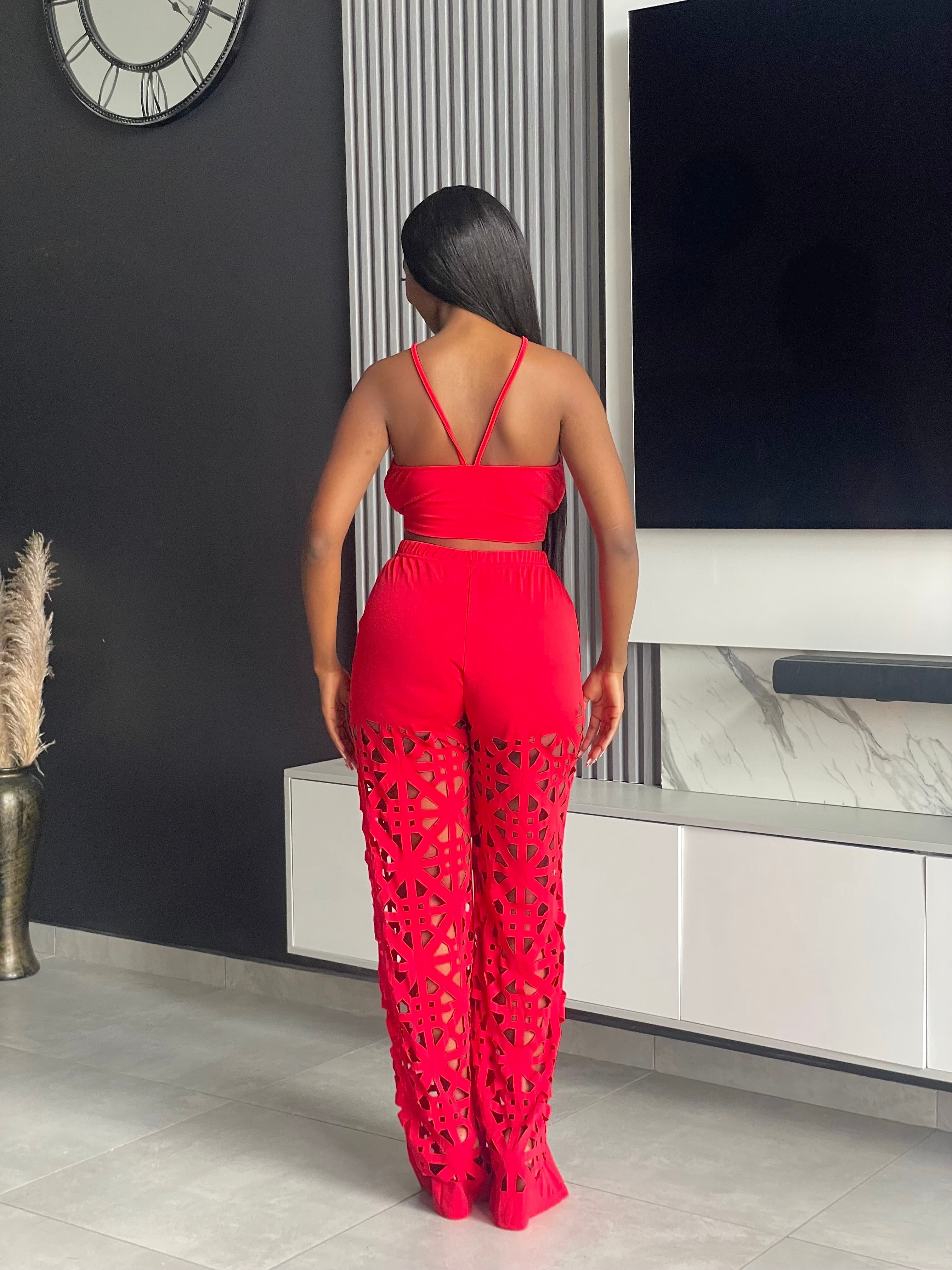 Model wearing the Remedy Pant Set in red, featuring a crisscross halter crop top and wide-leg pants with intricate cutout designs.