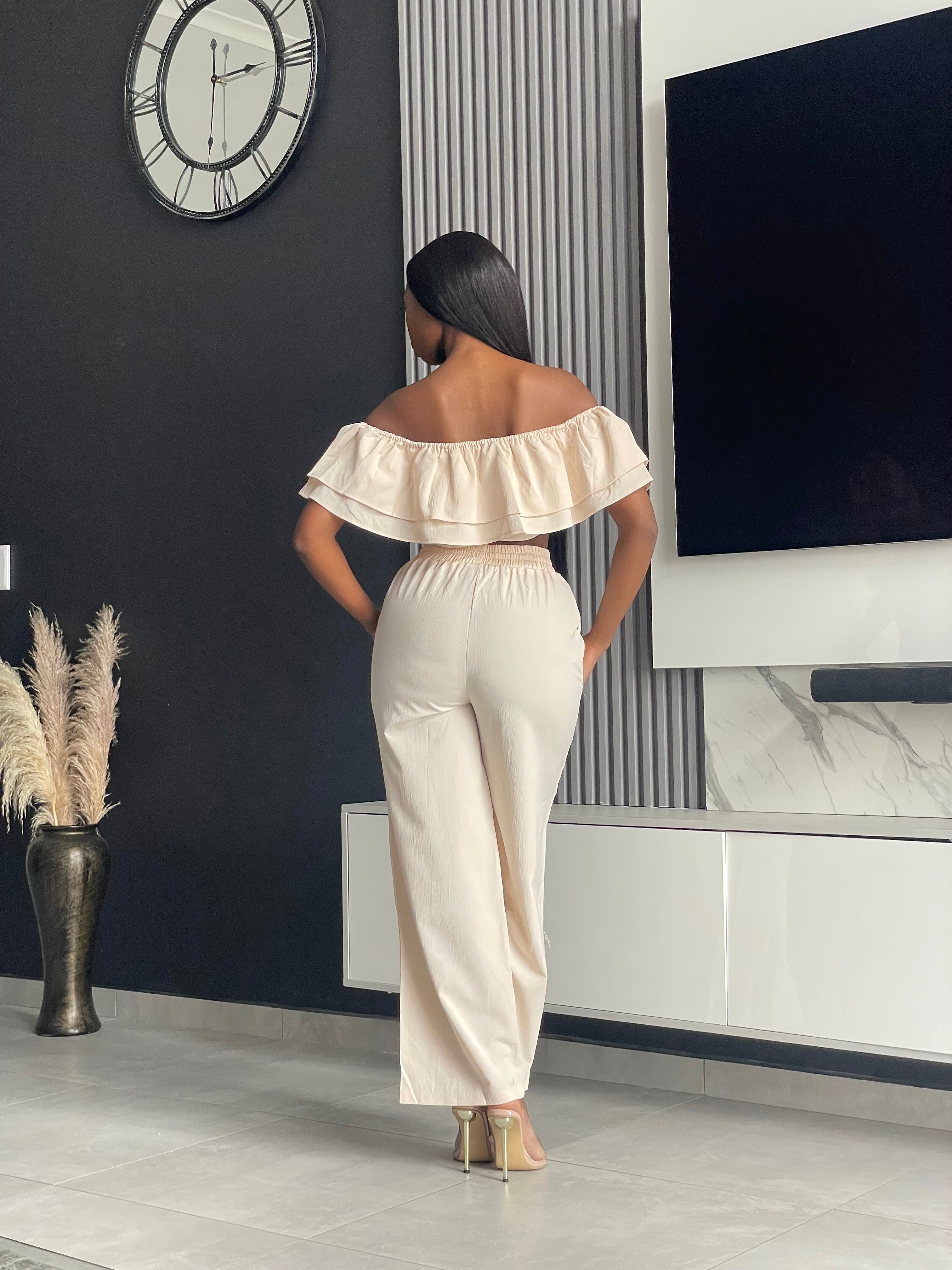 Model wearing the Varouna Pant Set in beige, featuring an off-shoulder ruffled crop top and wide-leg pants, perfect for casual outings.