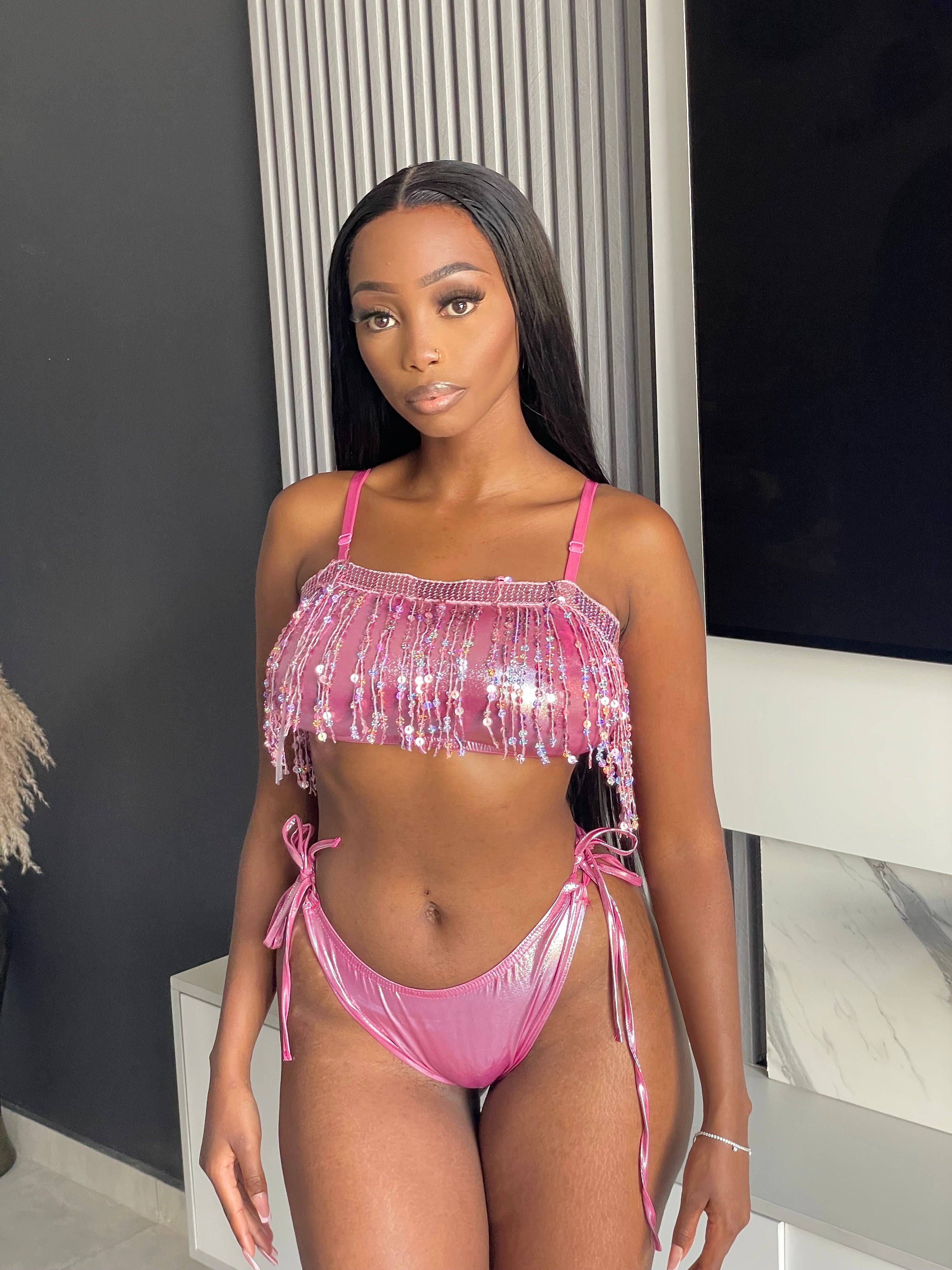 Model wearing the Auja Bikini, a pink sequin two-piece set featuring a fringe crop top and adjustable side-tie bottoms, perfect for beach days or poolside glamour.