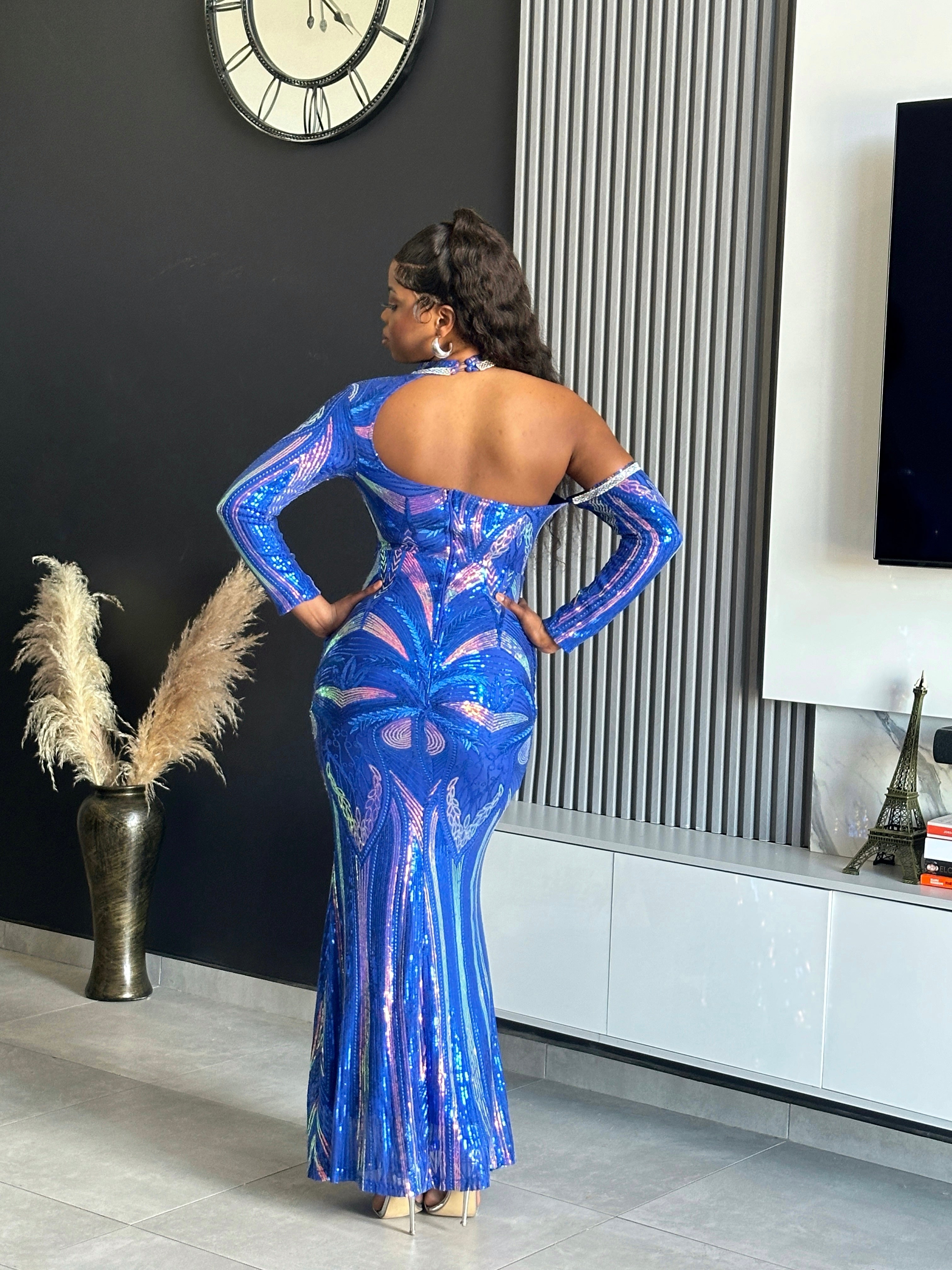 A woman wearing the Glammed Up Shimmering Blue Maxi Dress, featuring off-shoulder sleeves and sparkling details, perfect for elegant occasions