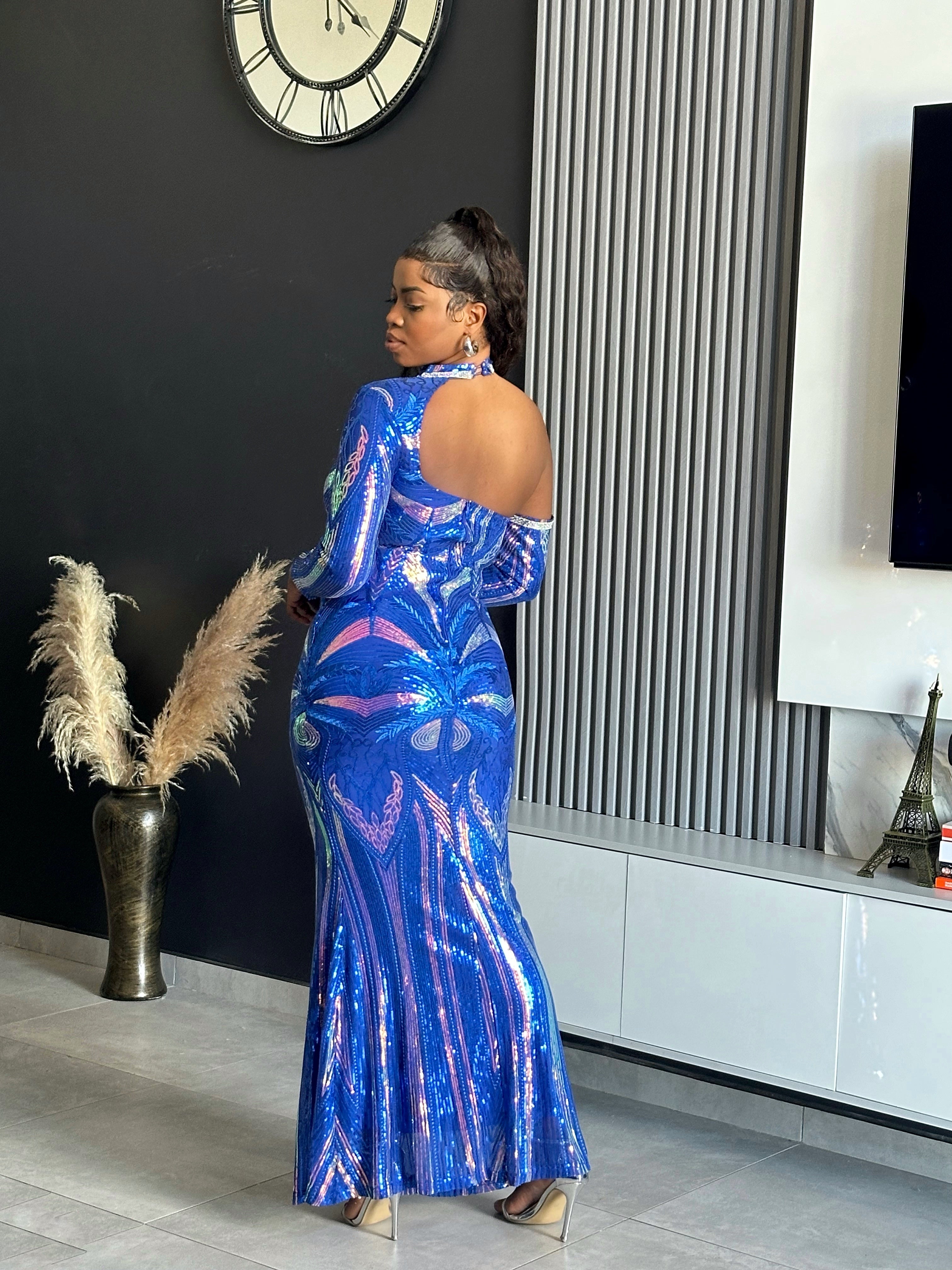 A woman wearing the Glammed Up Shimmering Blue Maxi Dress, featuring off-shoulder sleeves and sparkling details, perfect for elegant occasions