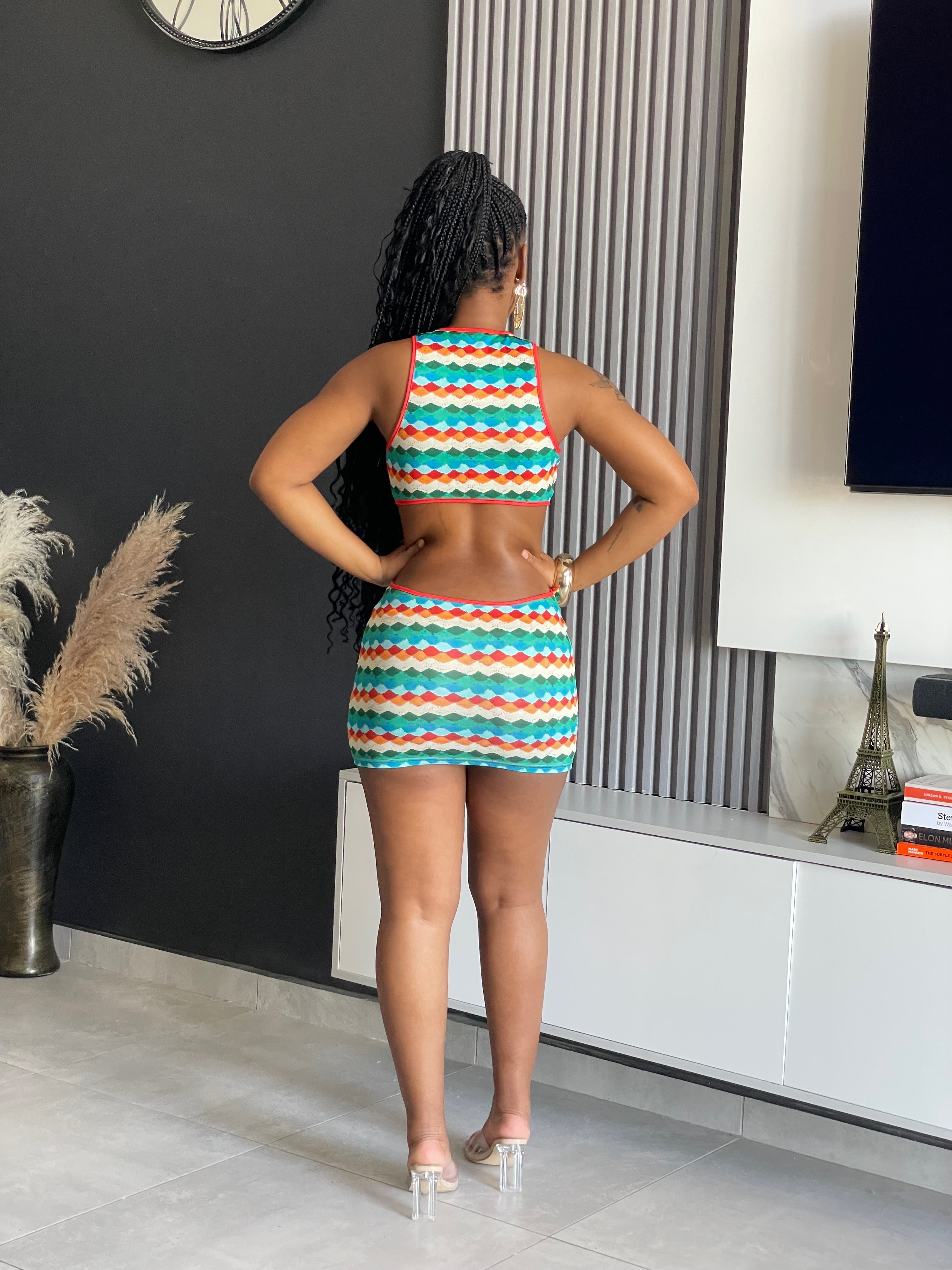 A woman wearing the Merit Cut-Outs Mini Dress, featuring vibrant wave patterns and stylish cut-outs, perfect for upscale events