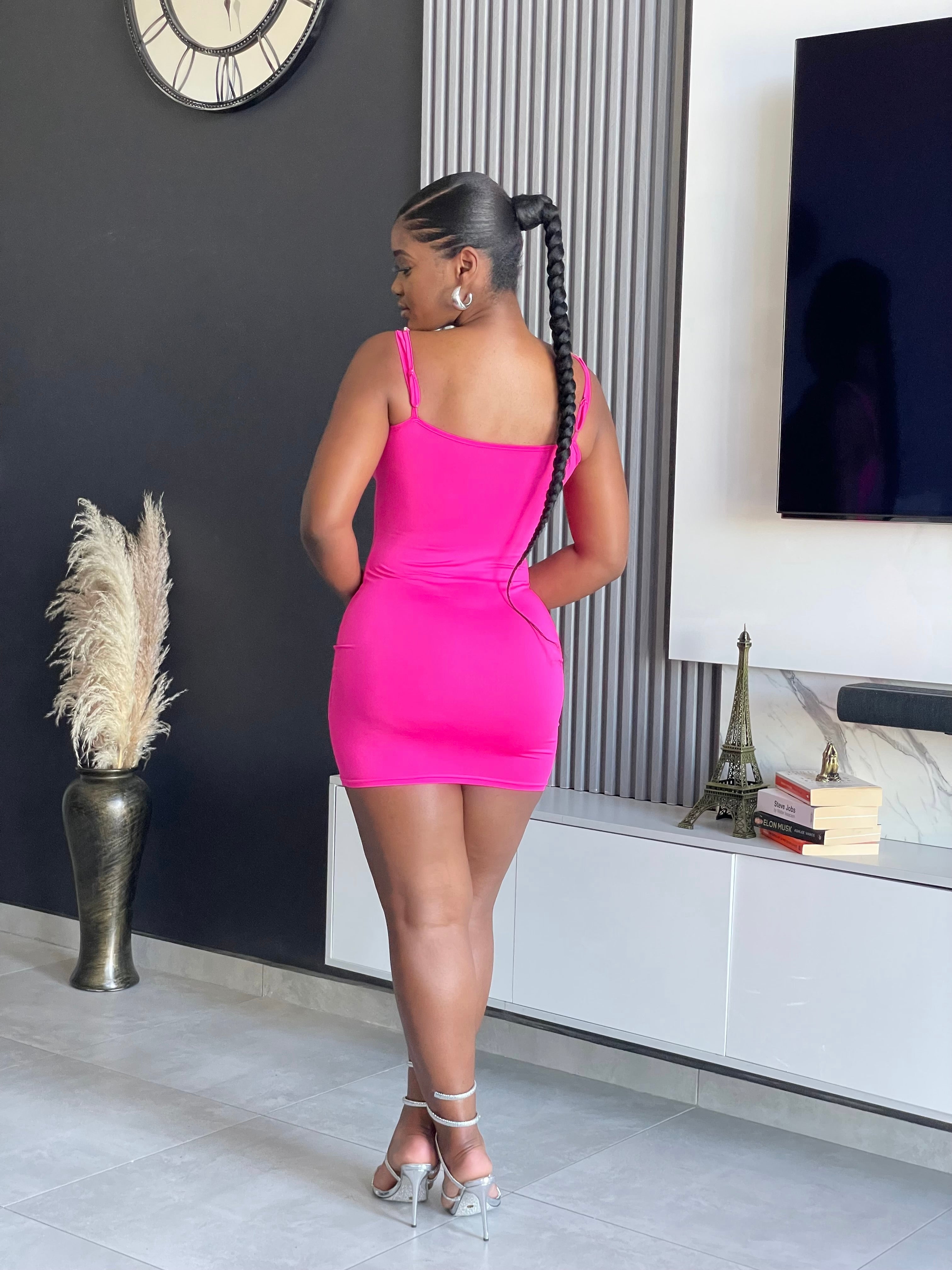 A woman wearing the Sace Bodycon Mini Dress in vibrant pink, perfect for enhancing your party wardrobe with its unique strap details and snug fit.