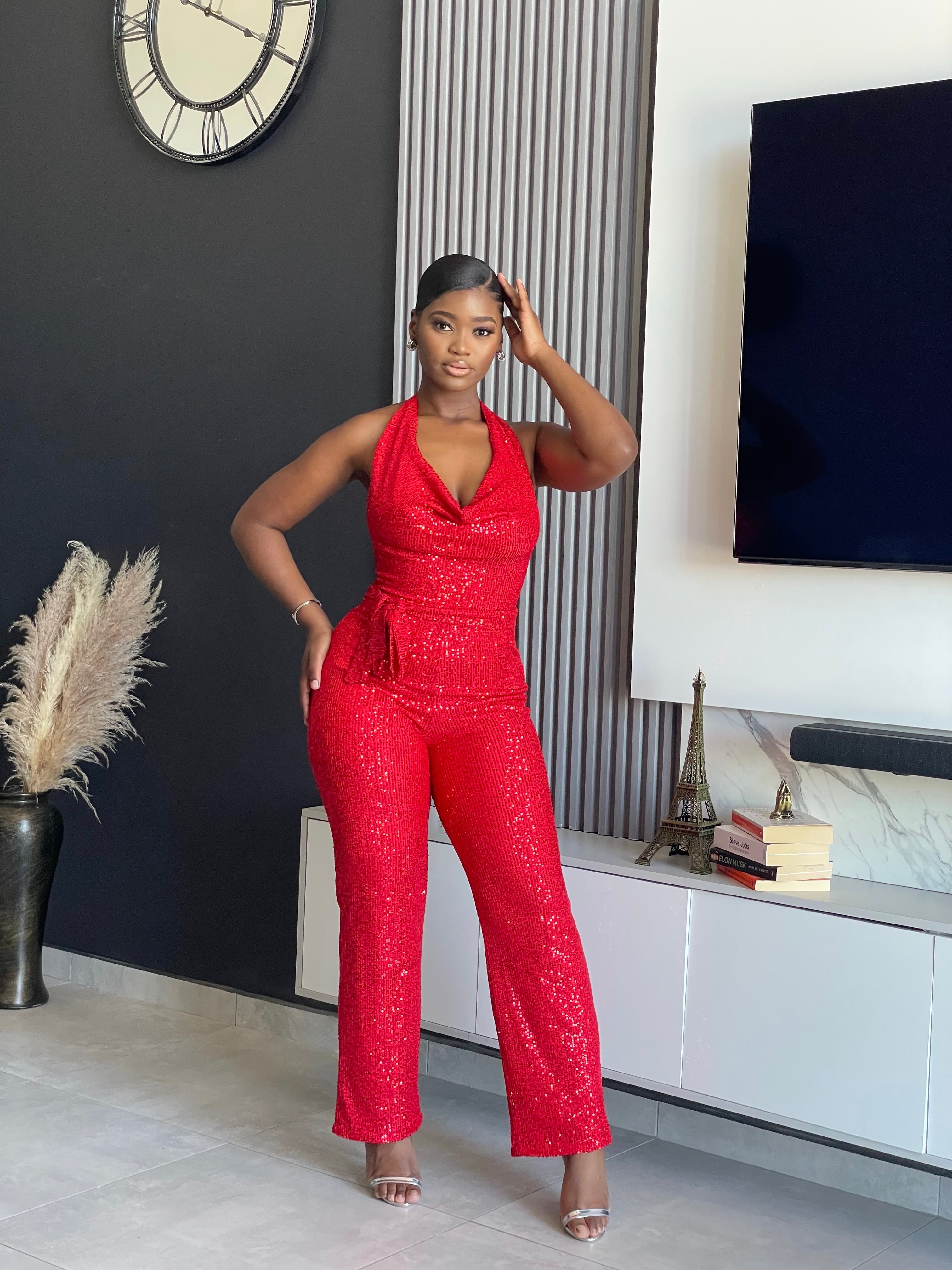 A woman wearing the Bday Sparkle Glitter Jumpsuit in sparkling red, designed for celebratory occasions and birthday parties