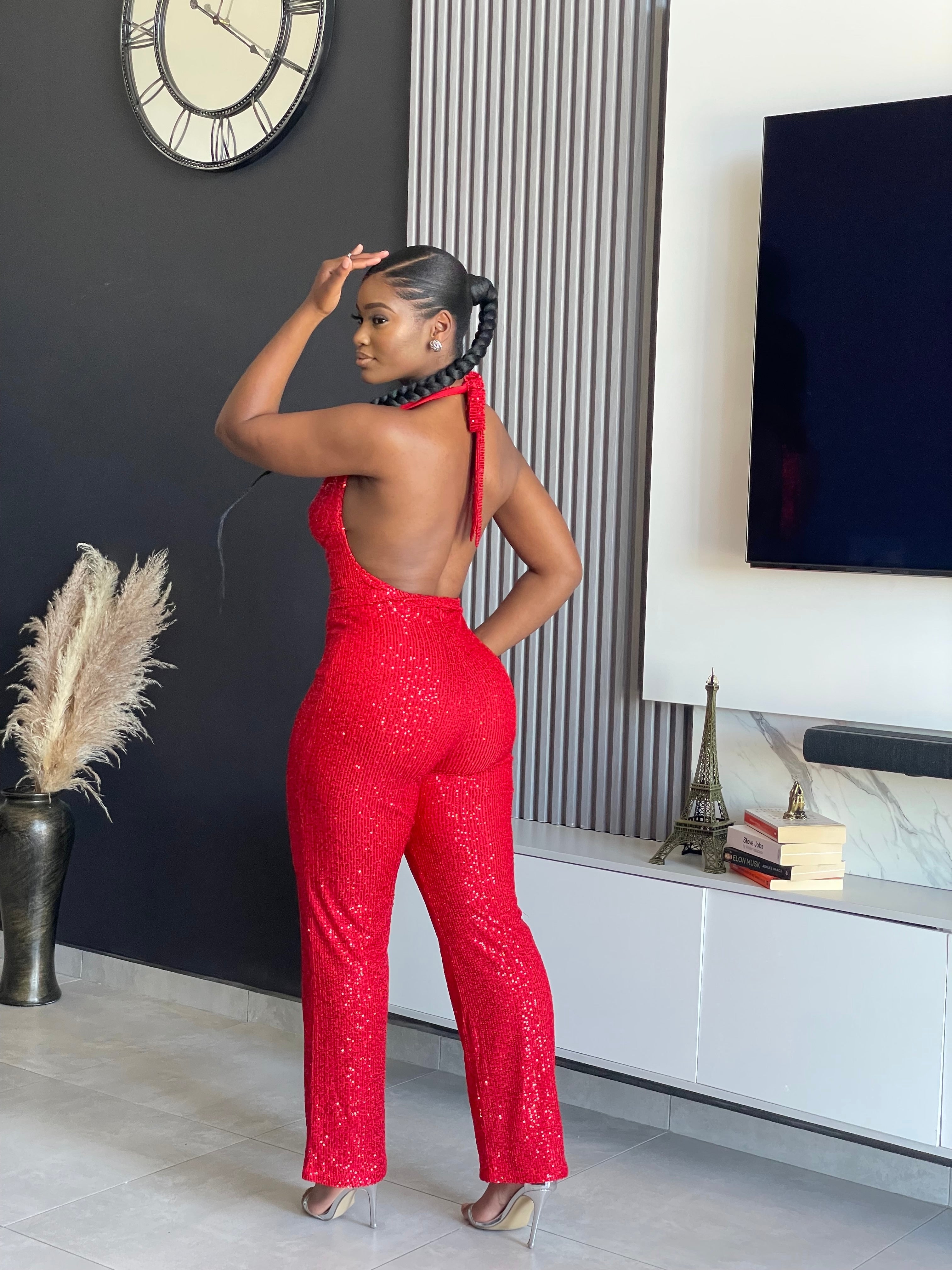 A woman wearing the Bday Sparkle Glitter Jumpsuit in sparkling red, designed for celebratory occasions and birthday parties