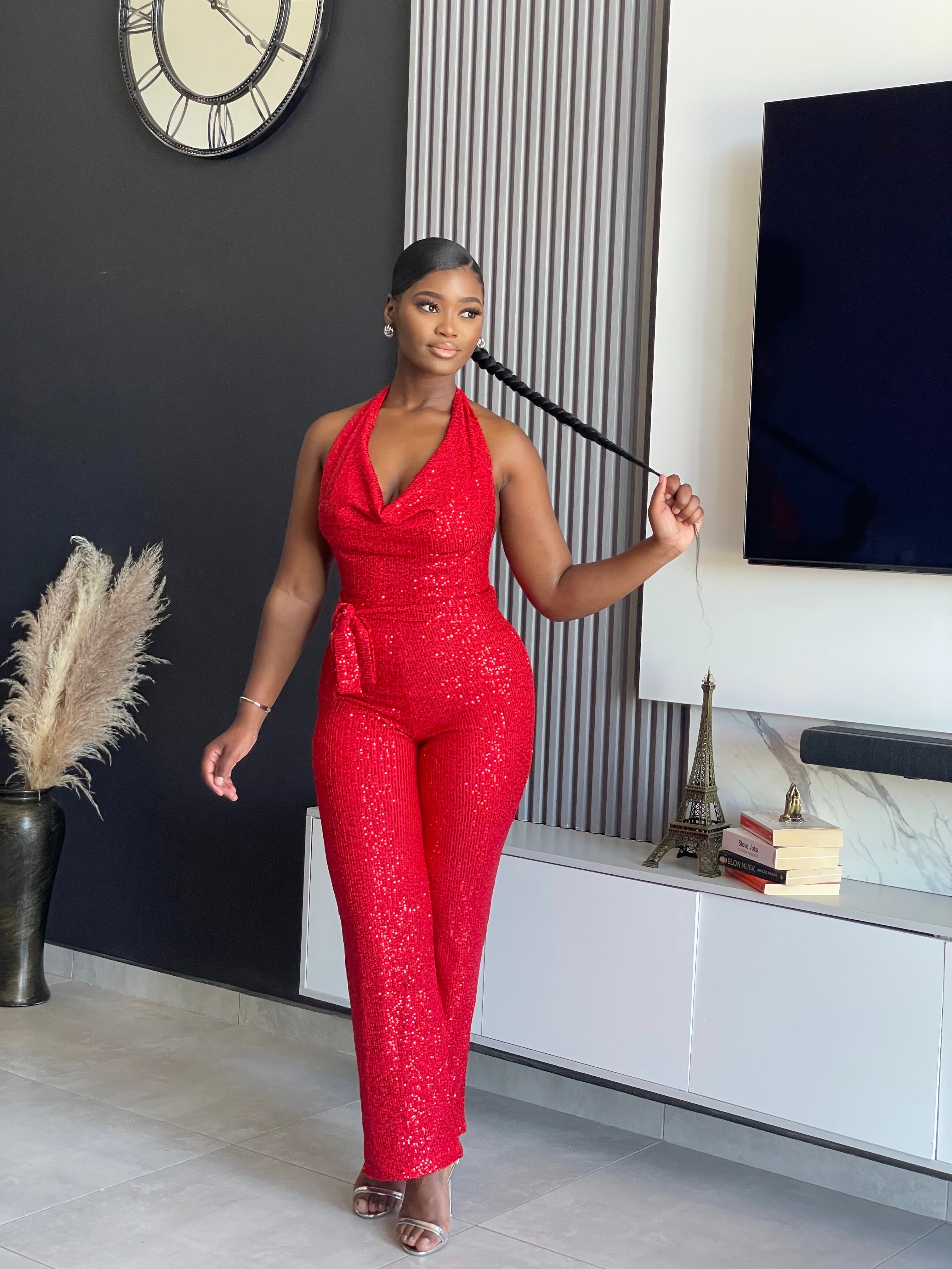 A woman wearing the Bday Sparkle Glitter Jumpsuit in sparkling red, designed for celebratory occasions and birthday parties