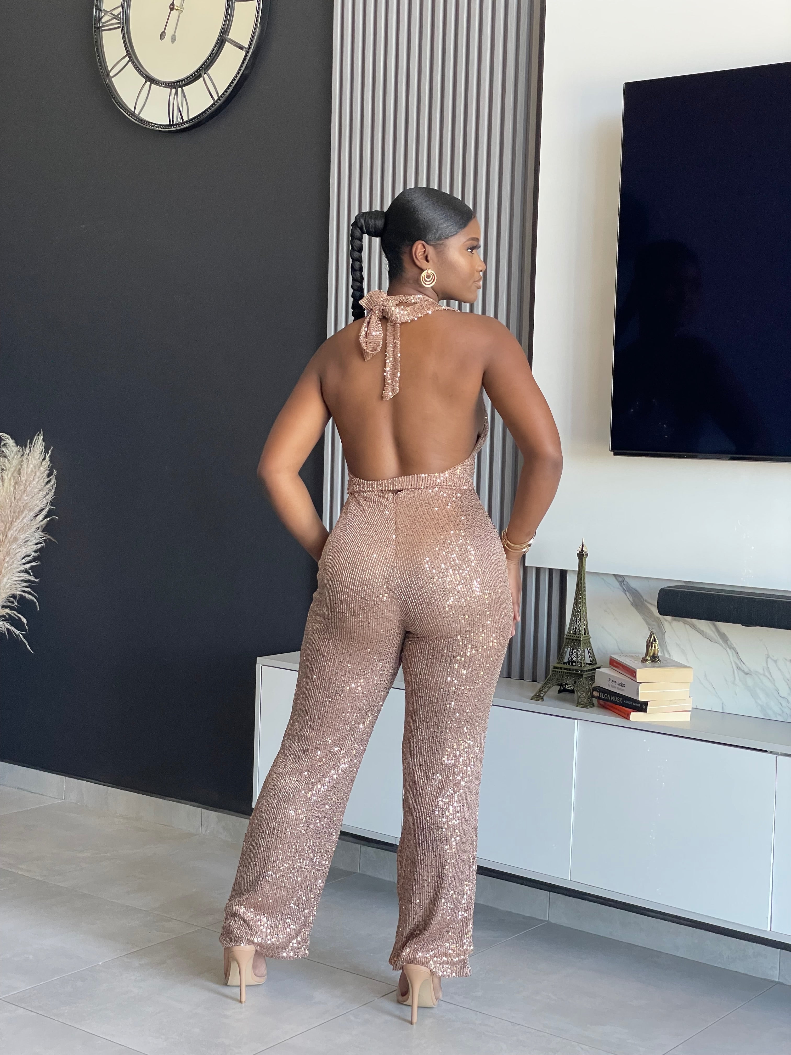 A woman wearing the Bday Sparkle Sequin Jumpsuit, a glamorous sequin-embellished outfit with a halter neckline and belted waist, perfect for special celebrations.