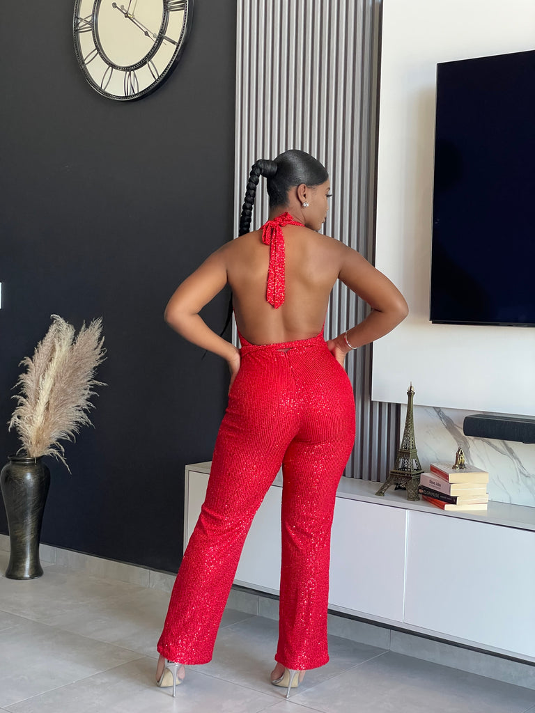 A woman wearing the Bday Sparkle Glitter Jumpsuit in sparkling red, designed for celebratory occasions and birthday parties