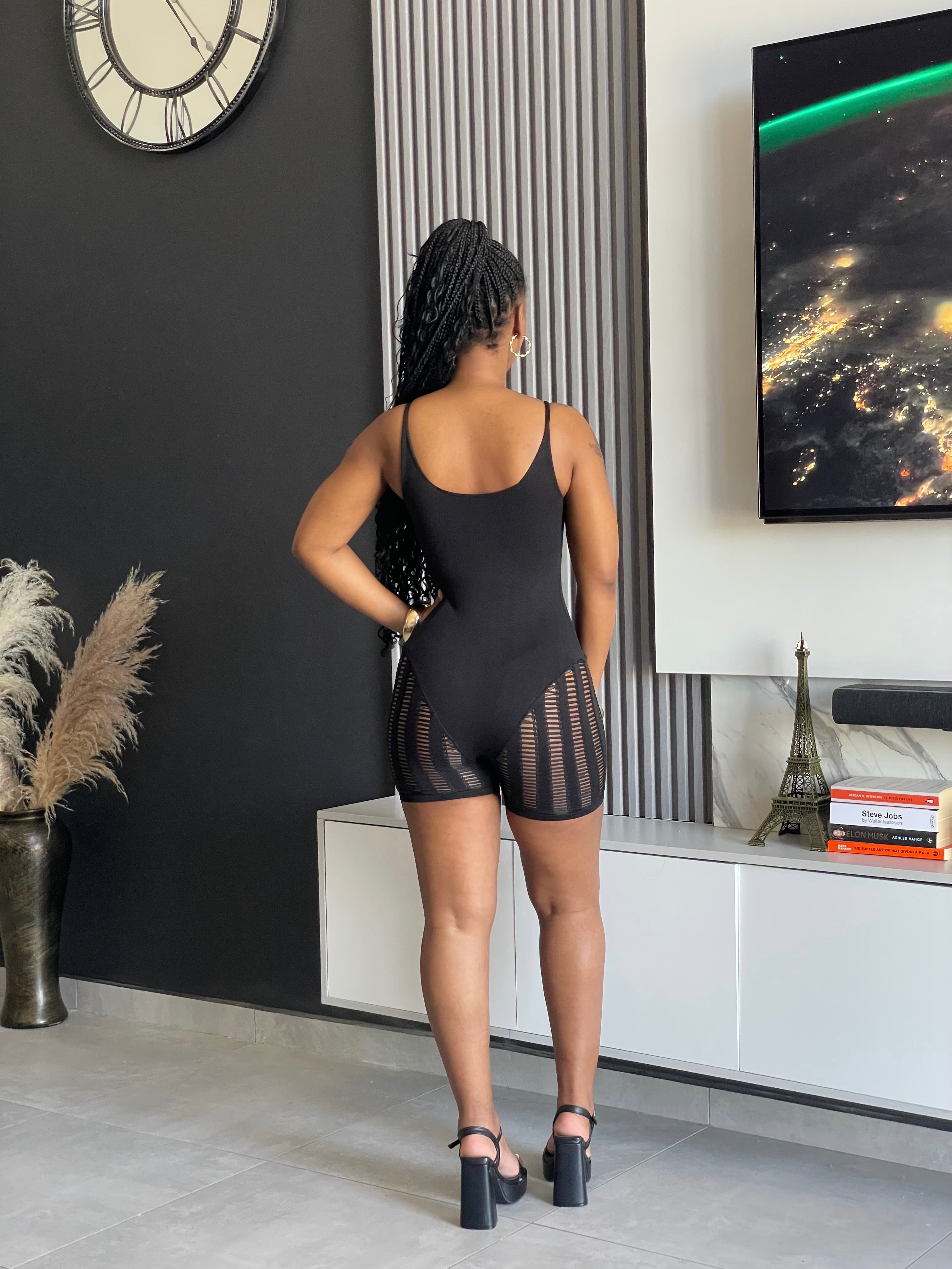 A woman wearing the Sel Mesh Panel Romper in black, highlighting its stylish mesh side panels and sleek design, ideal for a trendy look.
